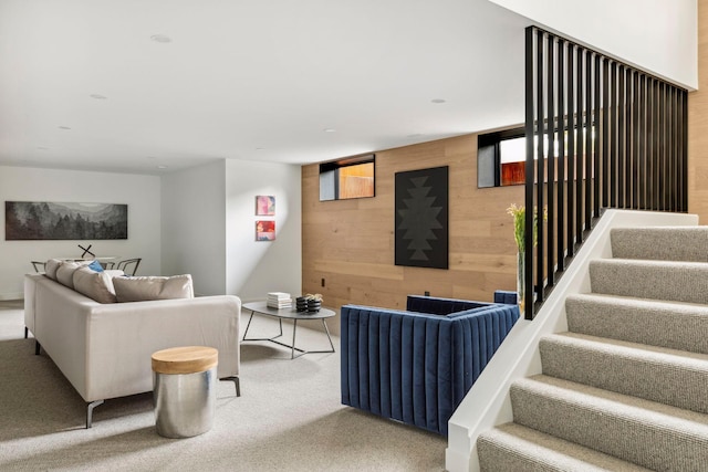 carpeted living room featuring wooden walls