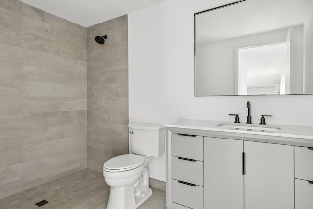 bathroom featuring tiled shower, vanity, and toilet