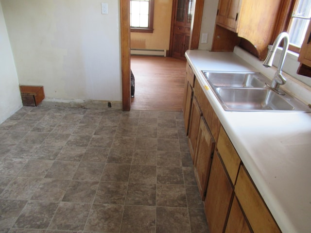 kitchen featuring a baseboard radiator, brown cabinets, a sink, and light countertops