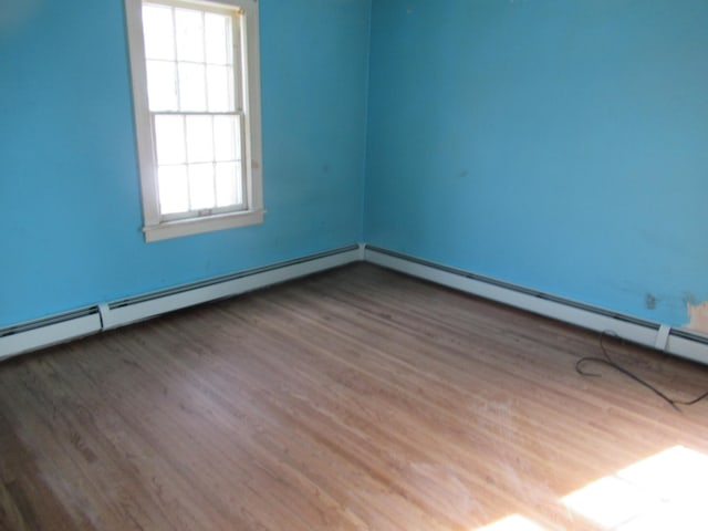 spare room featuring baseboard heating, a baseboard radiator, and wood finished floors