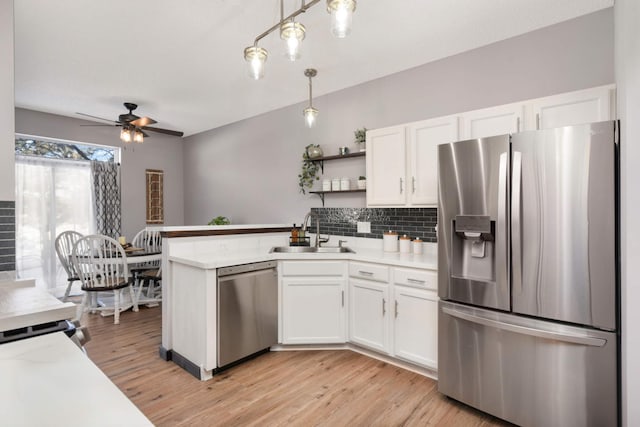 kitchen featuring a sink, white cabinets, hanging light fixtures, appliances with stainless steel finishes, and light countertops