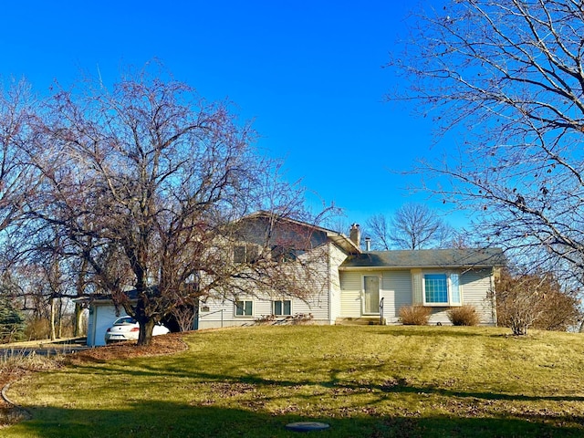 rear view of house with a garage and a yard