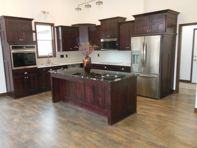 kitchen with stainless steel appliances, dark hardwood / wood-style flooring, sink, and a kitchen island