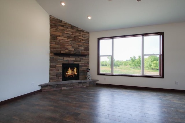 unfurnished living room with a stone fireplace, vaulted ceiling, and dark hardwood / wood-style floors