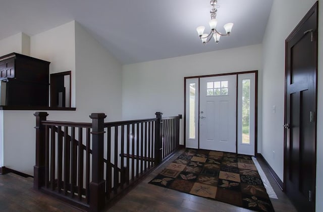 foyer with lofted ceiling, dark hardwood / wood-style flooring, and a chandelier