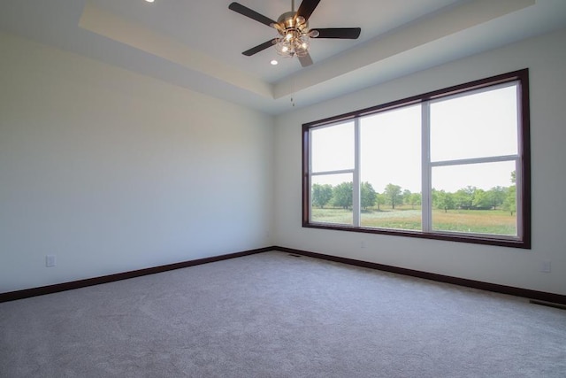 carpeted empty room with a tray ceiling and ceiling fan