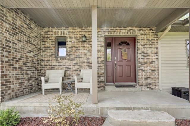 entrance to property featuring covered porch and brick siding