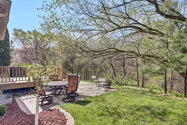 view of yard featuring outdoor dining space, a deck, and a patio