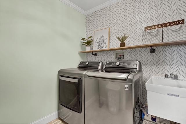 laundry room with washing machine and dryer, laundry area, a sink, ornamental molding, and wallpapered walls