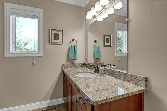 bathroom with ornamental molding, vanity, and baseboards