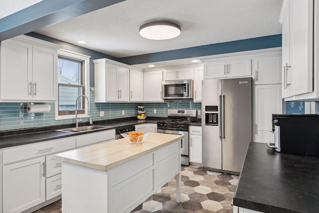 kitchen with sink, white cabinets, stainless steel appliances, and a center island