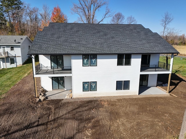 back of property with a balcony, a yard, and a patio area