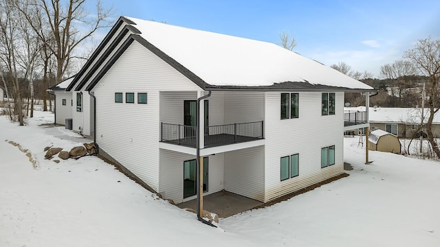 snow covered house featuring a balcony