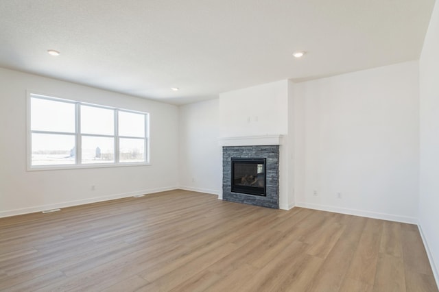 unfurnished living room featuring a fireplace and light hardwood / wood-style floors