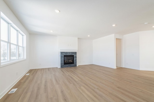 unfurnished living room featuring a fireplace and light hardwood / wood-style floors