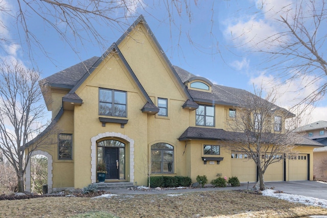 view of front of home featuring aphalt driveway, roof with shingles, a garage, and stucco siding