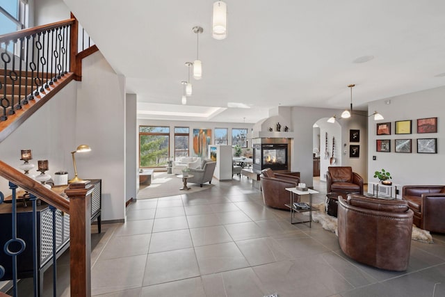 tiled living room featuring stairs, arched walkways, and a multi sided fireplace