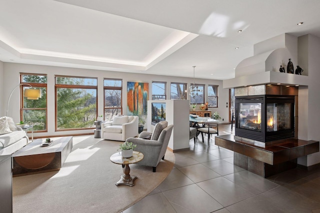 living area featuring a tiled fireplace, tile patterned floors, a wealth of natural light, and a notable chandelier