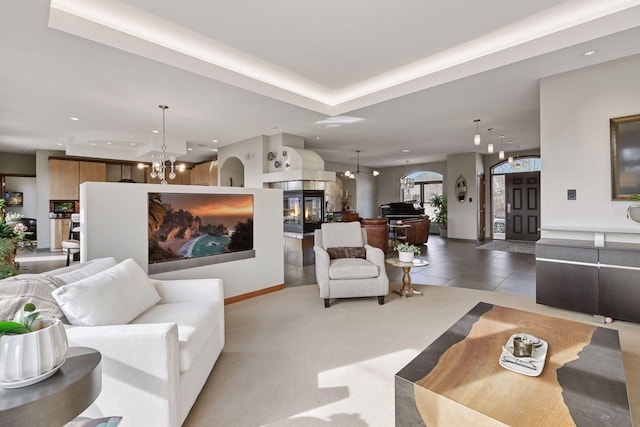 tiled living room featuring recessed lighting, baseboards, a multi sided fireplace, and an inviting chandelier