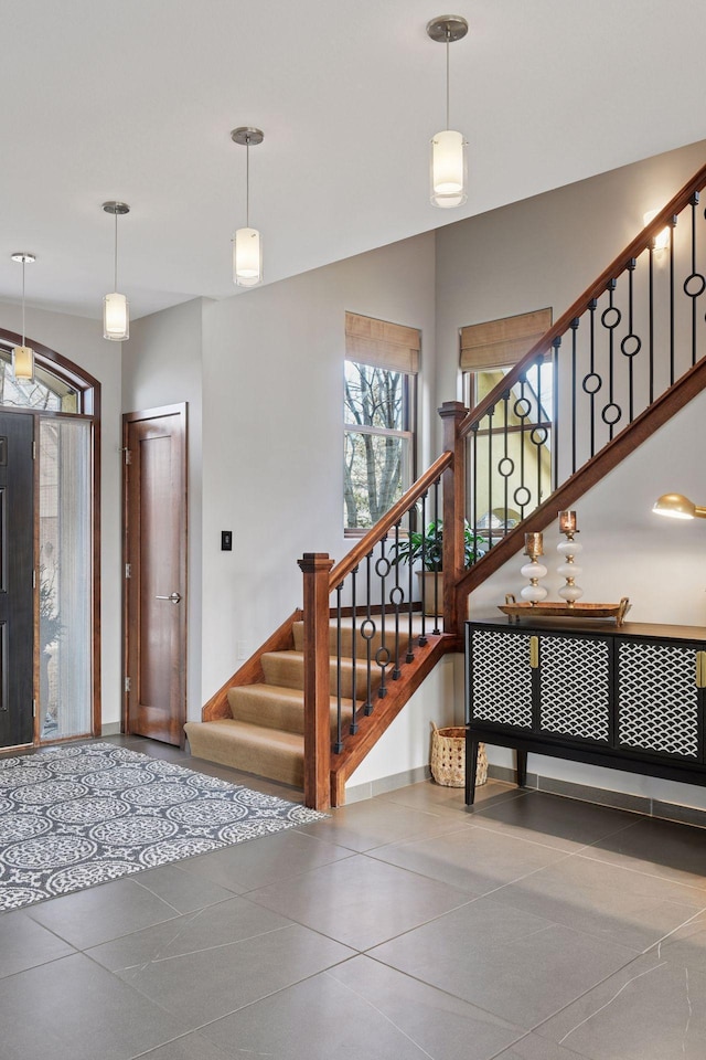 tiled entrance foyer featuring stairway and baseboards