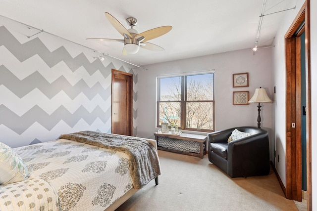 bedroom with wallpapered walls, baseboards, light colored carpet, ceiling fan, and an accent wall