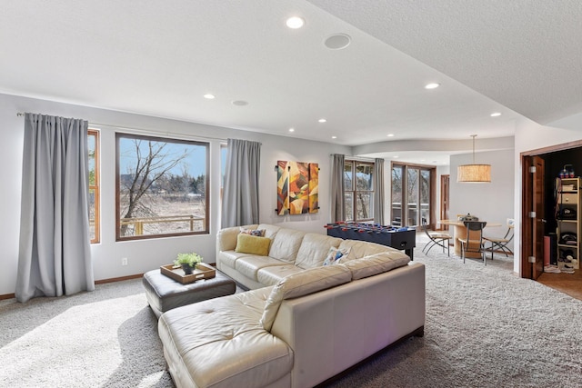 carpeted living area featuring baseboards, a textured ceiling, and recessed lighting