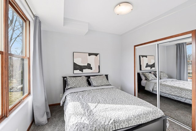 carpeted bedroom with a closet and baseboards