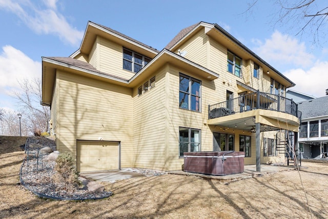 back of property with stairway, a patio area, a hot tub, and an attached garage