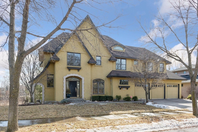 view of front of house featuring a shingled roof, concrete driveway, and stucco siding