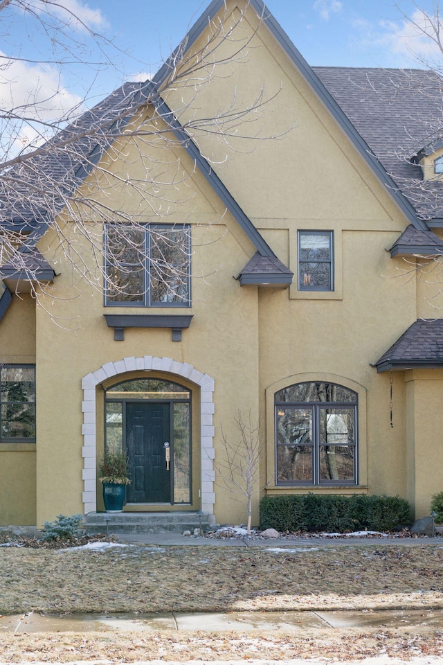 exterior space with a shingled roof and stucco siding