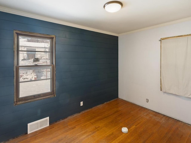 empty room featuring hardwood / wood-style flooring, crown molding, and a wealth of natural light