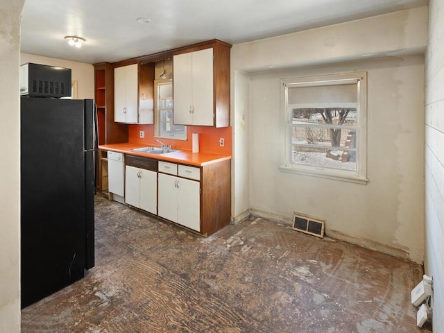 kitchen with white cabinetry, white dishwasher, sink, and black fridge