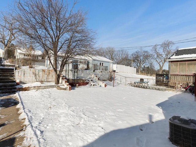 yard layered in snow featuring central AC unit