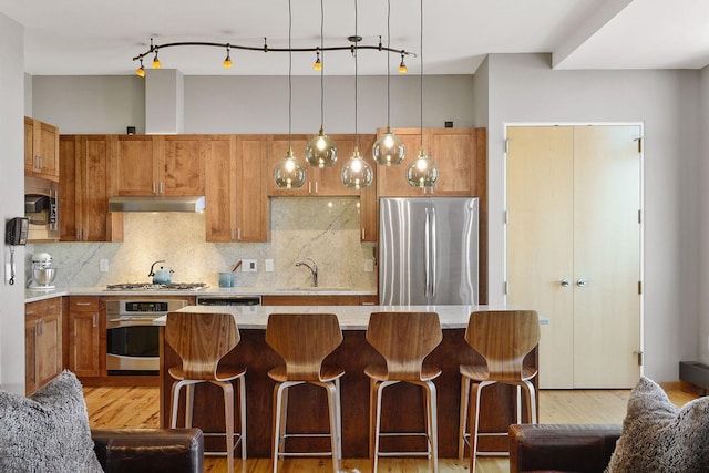 kitchen featuring a kitchen island, sink, decorative backsplash, light stone counters, and stainless steel appliances