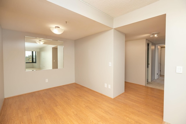 unfurnished room featuring a textured ceiling and light wood-type flooring