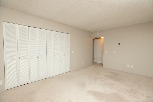 unfurnished bedroom featuring carpet flooring, a textured ceiling, and a closet