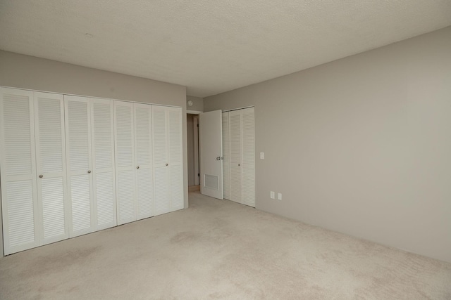 unfurnished bedroom featuring light carpet and a textured ceiling