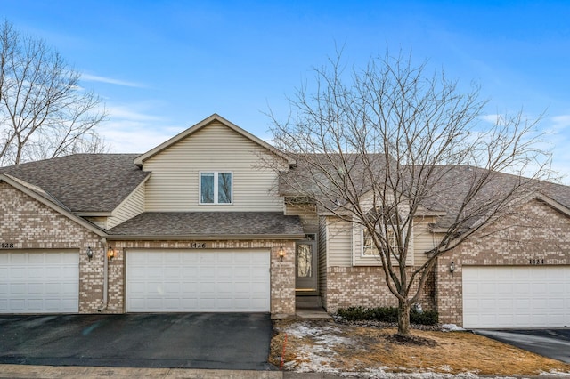 view of front of property with a shingled roof, aphalt driveway, and brick siding