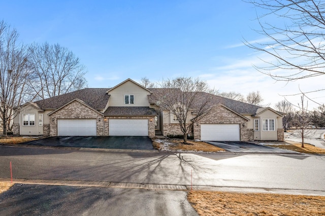 view of front of home featuring a garage, aphalt driveway, roof with shingles, and brick siding