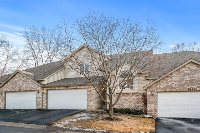 view of front of house featuring a garage, brick siding, a shingled roof, and aphalt driveway