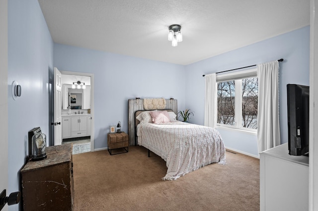 bedroom featuring carpet floors, visible vents, a textured ceiling, ensuite bath, and baseboards