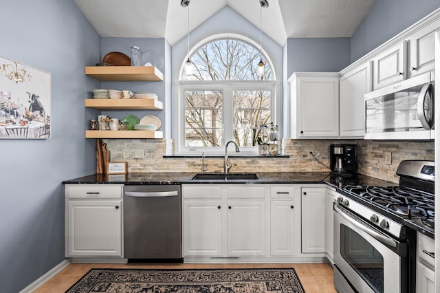 kitchen featuring stainless steel appliances, light tile patterned floors, white cabinetry, and a sink