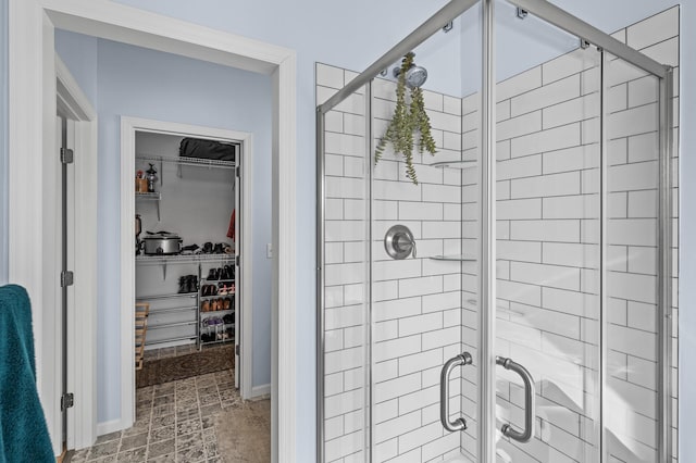 bathroom with baseboards, a walk in closet, and a shower stall