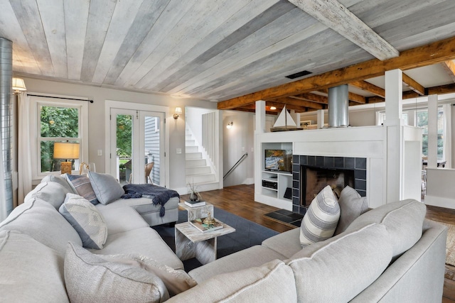 living room with dark hardwood / wood-style flooring, a tiled fireplace, beam ceiling, and wooden ceiling