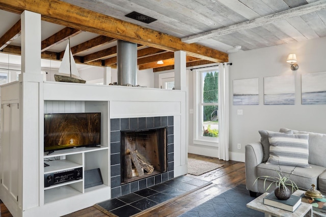 living room with beamed ceiling, a tiled fireplace, and dark hardwood / wood-style flooring