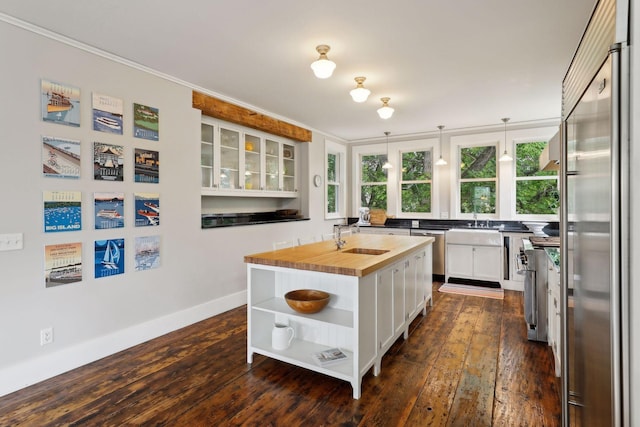 kitchen with sink, white cabinetry, wooden counters, appliances with stainless steel finishes, and a kitchen island