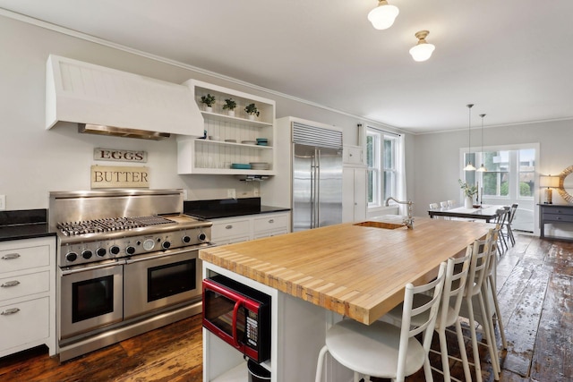 kitchen with high quality appliances, a kitchen breakfast bar, a kitchen island with sink, and custom exhaust hood