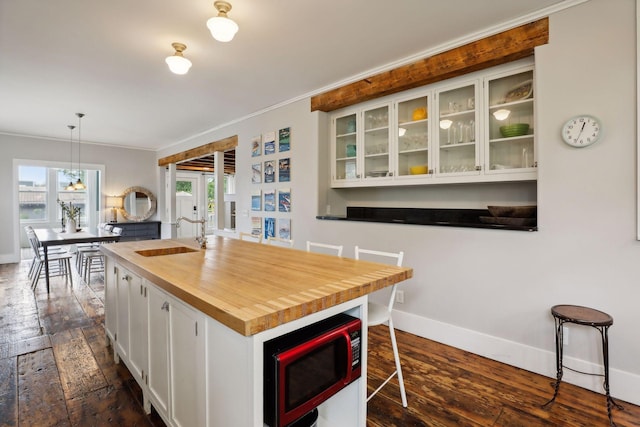 kitchen featuring sink, white cabinetry, decorative light fixtures, dark hardwood / wood-style flooring, and a kitchen breakfast bar