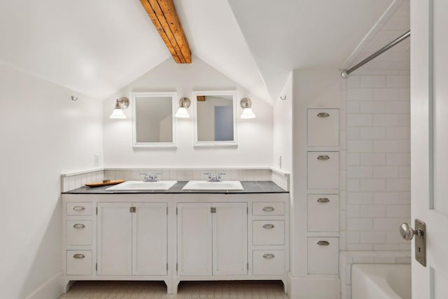 bathroom featuring lofted ceiling with beams, tiled shower / bath, and vanity