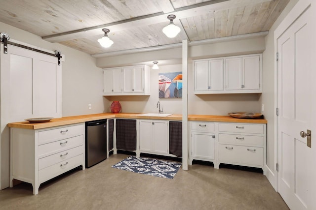 kitchen featuring white cabinetry, a barn door, sink, and wood counters